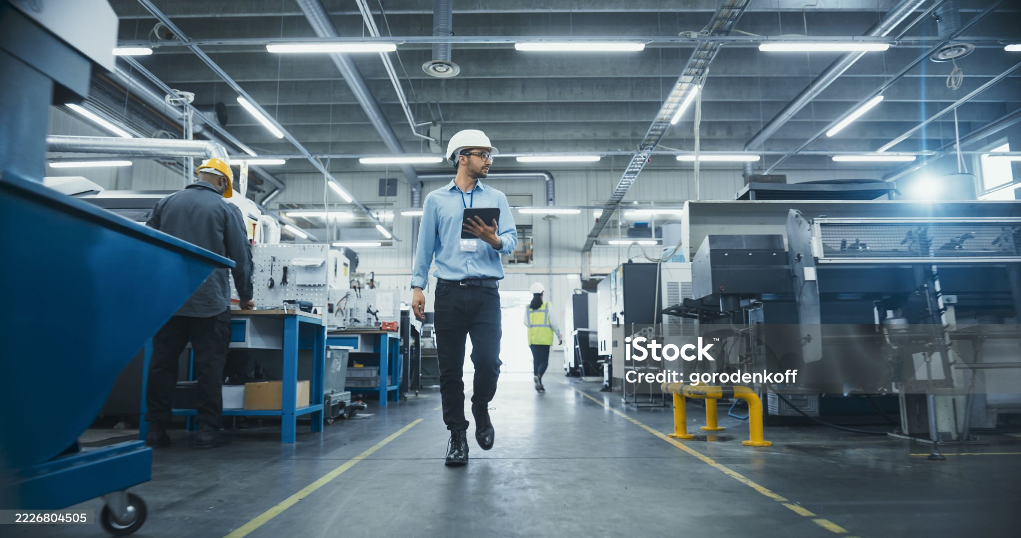 Site supervisor with a tablet observing a plant operator at work